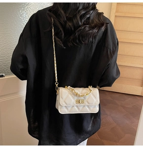 Détail d'un sac bandoulière matelassé beige avec fermoir doré et bandoulière en chaîne