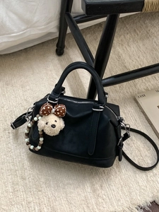Classic black Boston bag in soft leather with a cute puppy charm on a modern chair