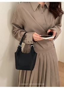 Minimalist black lychee texture bucket bag with silver buckle details shown on model