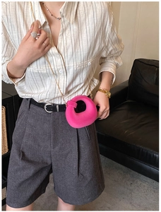 Detail of bright pink ring-shaped crossbody bag with a fine gold chain strap