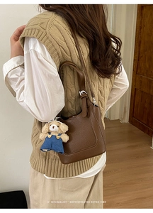 Brown litchi grain leather bucket bag featuring a cute teddy bear plush charm detail