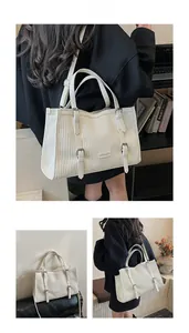 Detail view of white pleated tote bag with fashion metal logo and buckle decoration