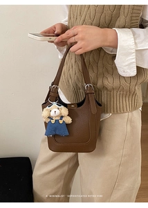 Detail of retro brown bucket bag featuring a leather texture and cute bear charm