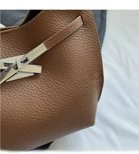 Detailed close-up of brown pebble grain leather and iconic silver T-lock metal buckle