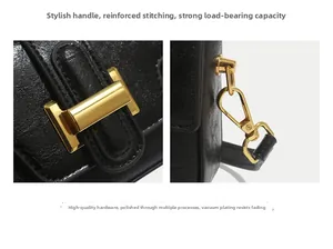 Detail of black leather handbag featuring golden hardware and reinforced stitching on handles
