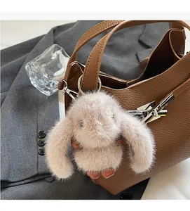 Brown lychee leather bucket bag detail with a cute fluffy grey bunny charm and silver hardware