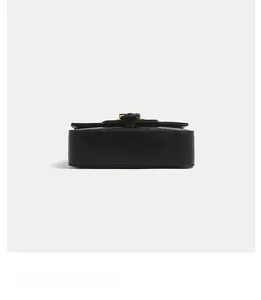 Detail showing smooth leather bottom stitching and golden metal clasp on black handbag
