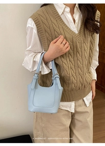 Close-up of light blue mini bucket bag with litchi texture on model shoulder