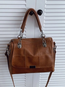 Brown Boston handbag with grid stitching, metal chain straps, and a shoulder strap
