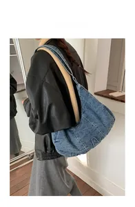 Detailed view of a large denim hobo bag worn by a model in a casual street style outfit