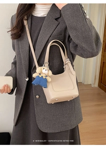 Beige bucket bag with lychee texture leather and cute bear charm shown on model