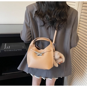 Detail of light brown lychee grain leather bucket bag with silver lock and plush bunny charm