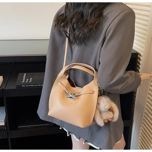 Detail of light brown lychee grain leather bucket bag with metal lock and plush bunny charm