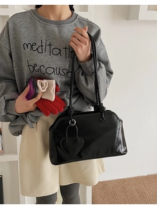 Close-up of black glossy tote bag with heart charm and decorative knot details