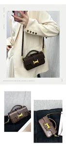 Brown textured leather crossbody bag detail featuring a golden H-buckle and retro design