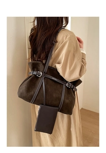 Detail of dark brown suede tote bag featuring pleated texture and decorative buckle strap