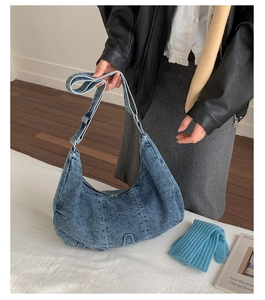 Close-up of washed denim hobo bag showing adjustable strap and silver metal buckle