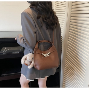 Brown litchi leather half-moon bag with silver buckle and plush rabbit keychain charm