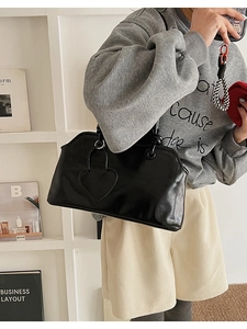 Close-up of black glossy tote bag with heart-shaped pocket on a model for daily use
