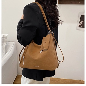 Close-up of brown PU leather tote bag with side pocket and logo detail worn by model