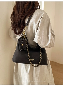 Close-up of matte black tote bag with gold chain and detachable mini envelope pouch