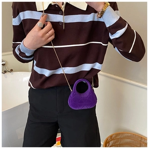 Close-up of a purple mini velvet crossbody bag with quilted pattern and gold chain strap