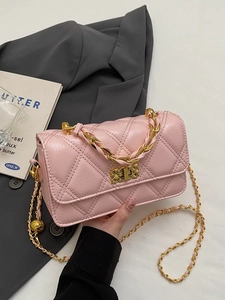 Sac baguette matelassé rose avec chaîne dorée et fermoir métallique sur blazer gris