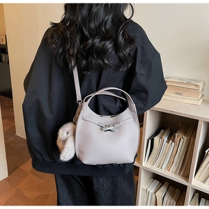 Detailed view of grey pebble leather handbag with silver H-buckle and plush rabbit charm