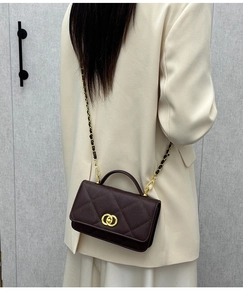 Deep burgundy quilted leather crossbody bag with chain strap and gold clasp on a model