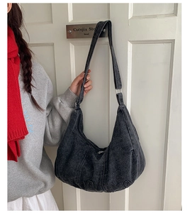 Black washed denim hobo bag worn over the shoulder for a retro casual street style look