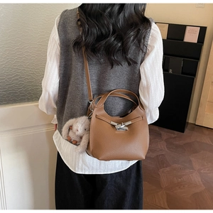 Close-up of brown lychee grain leather bucket bag with silver metal buckle and rabbit charm