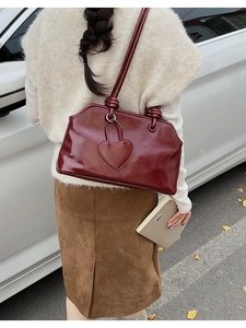 Detail of burgundy patent leather tote bag with heart patch and knotted shoulder strap