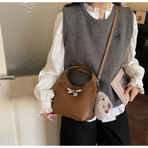 Detail of vintage brown lychee leather handbag with silver buckle and plush rabbit charm