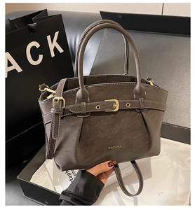 Detail of dark grey retro handbag with textured finish, metal buckle and branding logo