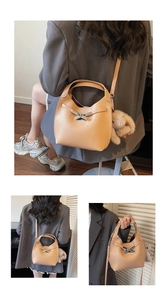 Close-up of camel bucket bag in lychee pattern leather with metal X buckle and bunny charm