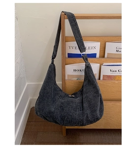 Detail of a dark grey washed denim hobo bag featuring a retro crescent half-moon design