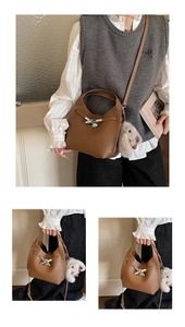 Detail of a brown lychee pattern leather bucket bag with silver lock and plush bunny