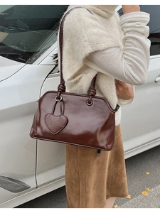 Detail of a shiny chocolate brown tote bag with decorative knots and heart charm accessory
