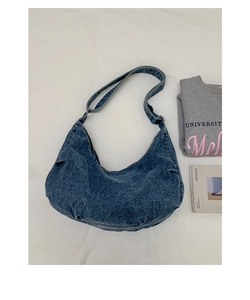 Flat lay of a medium blue washed denim crescent crossbody bag with an adjustable strap