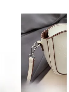 Close-up of cream square bag with brown edge finish and silver metal hardware details