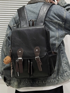 Vintage style large capacity black leather backpack shown in a lifestyle outdoor view