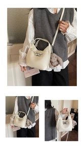 Detail of cream bucket bag with litchi texture, silver buckle and gray bunny charm