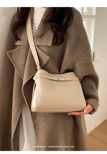 Gros plan d'un sac cabas en cuir beige avec fermoir rotatif argenté et large bandoulière