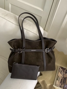 Large dark brown tote bag in brushed leather with contrast stitching on white sofa