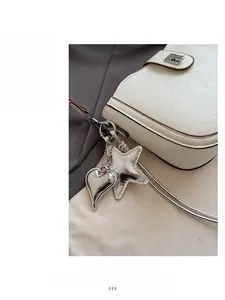 Detail of cream shoulder bag with silver heart charms and fine leather texture