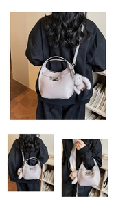 Detail of minimalist bucket bag with textured leather, knot hardware, and rabbit charm