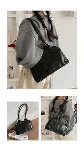 Detail of a retro black PU leather tote bag with a heart pendant and dual thin straps