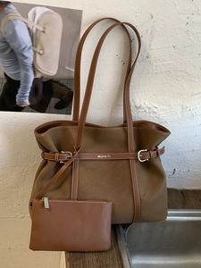 Brown canvas tote bag with leather strap and matching small pouch in a top-down view