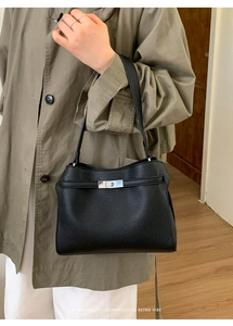 Gros plan du sac fourre-tout noir en cuir grainé avec fermoir argenté sur un manteau