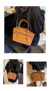 Detail of vintage brown leather handbag featuring gold metal buckle and pleated texture